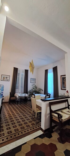 A dining area with a table, chairs, a water dispenser, and a patterned floor. - Villa Sunrise (Lucca)
