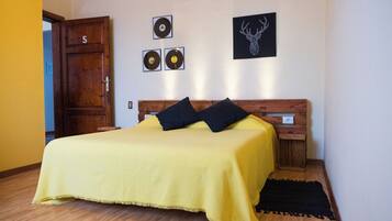 A bedroom with a bed, wooden headboard, a door, and wall decorations including vinyl records and a deer head.