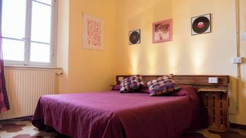 Een slaapkamer met een bed, een radiator, een raam en decoratie aan de muur.