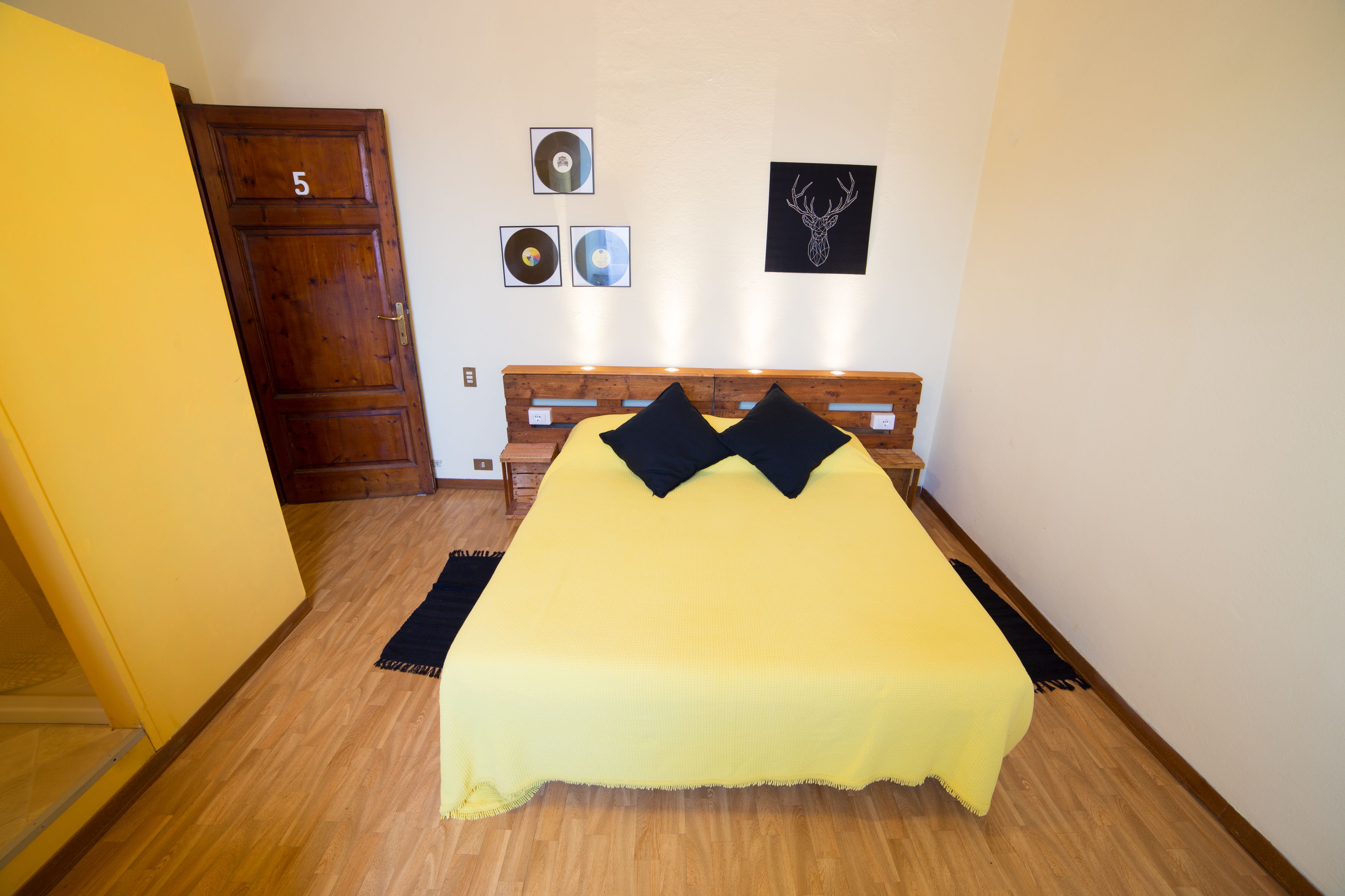 A room with a bed, wooden headboard, and a door marked with the number 5.