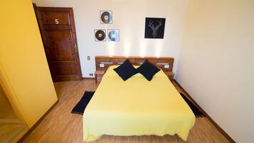 A room with a bed, wooden headboard, and a door marked with the number 5.