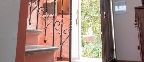 Una escalera con barandillas de metal decoradas conduce a un segundo piso. Se ve una puerta de madera y una ventana en la plataforma.