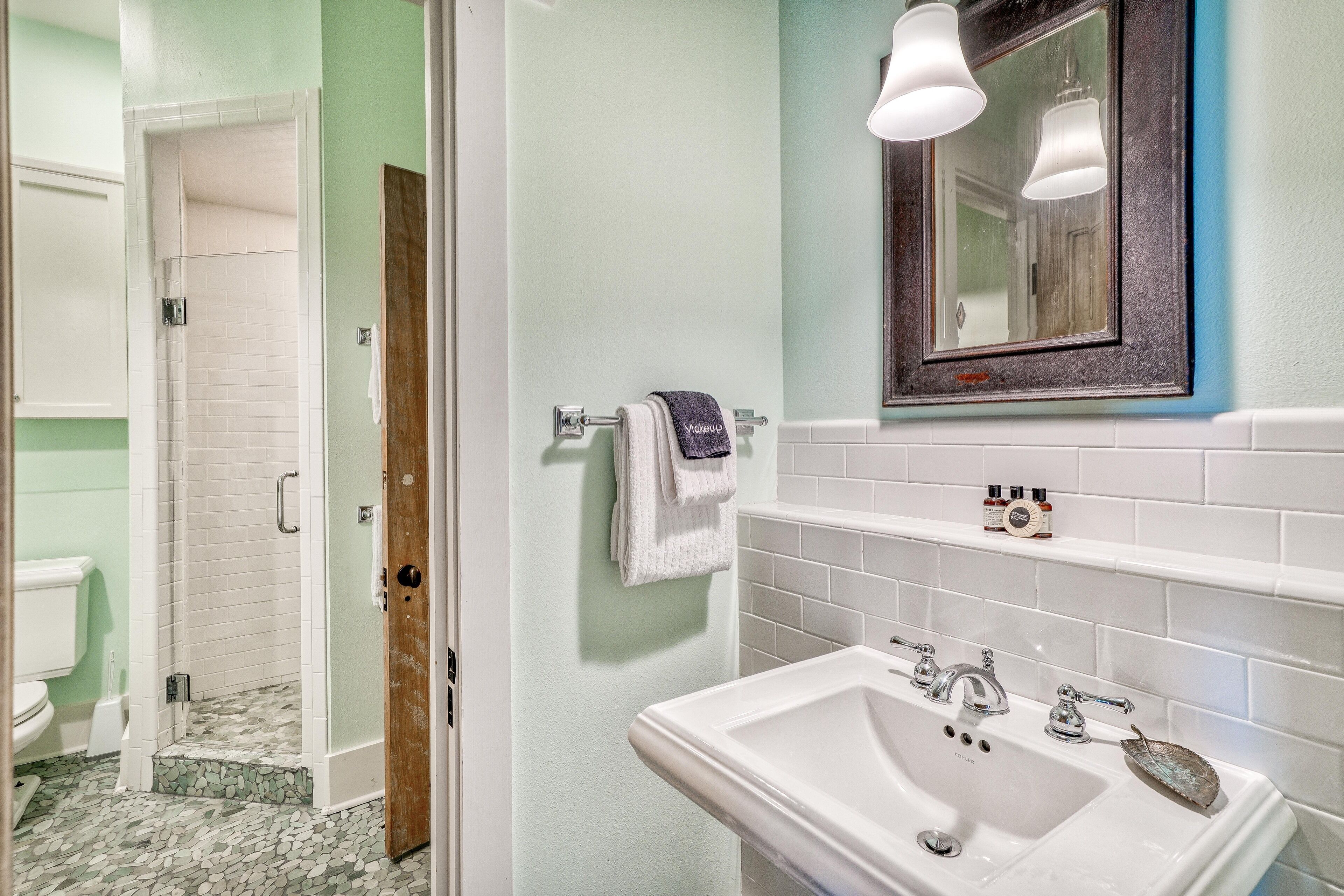 Un baño con lavamanos blanco, espejo y ducha.