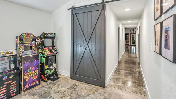 Un couloir agr émenté de jeux d’arcade, d’une porte coulissante de style grange et de tableaux encadrés accrochés au mur.