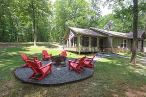 Eine Lodge mit überdachter Veranda, roten Adirondack-Stühlen, einer Feuerstelle und einer US-amerikanischen Flagge.