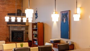 Ein Essbereich mit Kamin aus Backsteinen, hängenden Pendelleuchten und einer Bücherwand.