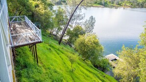 A balcony with a view of a lake, surrounded by lush greenery and trees. - Tulloch Lake House! Panoramic Views & Private Dock (Jamestown)