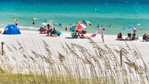 A beach with people, tents, and umbrellas.