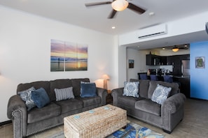 A living room with two grey sofas, a coffee table, and a painting of a sunset.