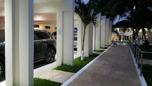 A modern hotel with a covered parking area, palm trees, and a pool area. - Casa Margarita Hotel And Paradise (Chiquimulilla)