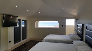 A bedroom with two beds, a TV, and a window with a view of the sea. - Casa Margarita Hotel And Paradise (Chiquimulilla)