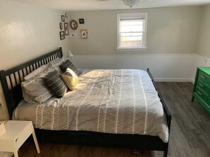 Un dormitorio con cama, ventana y cómoda verde.