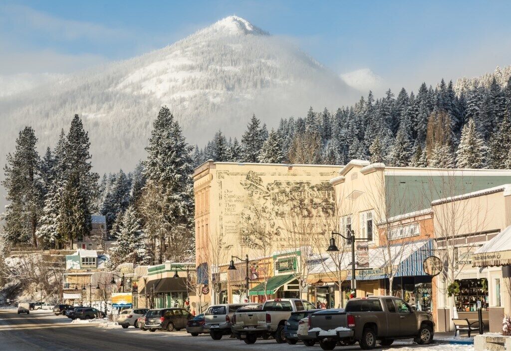 Uma cidade coberta de neve, com edifícios e carros estacionados.
