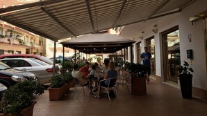 An outdoor patio with tables and chairs, surrounded by potted plants. - Hotel Arma (Taggia)