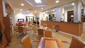 A restaurant with a counter, multiple tables, and chairs. - Hotel Arma (Taggia)
