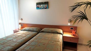 A double bed with patterned bedding, a bedside table with a lamp, and a wall-mounted painting.