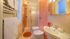 A bathroom with a glass shower enclosure, a toilet, a bidet, and a sink with a mirror. - Hotel Arma (Taggia)