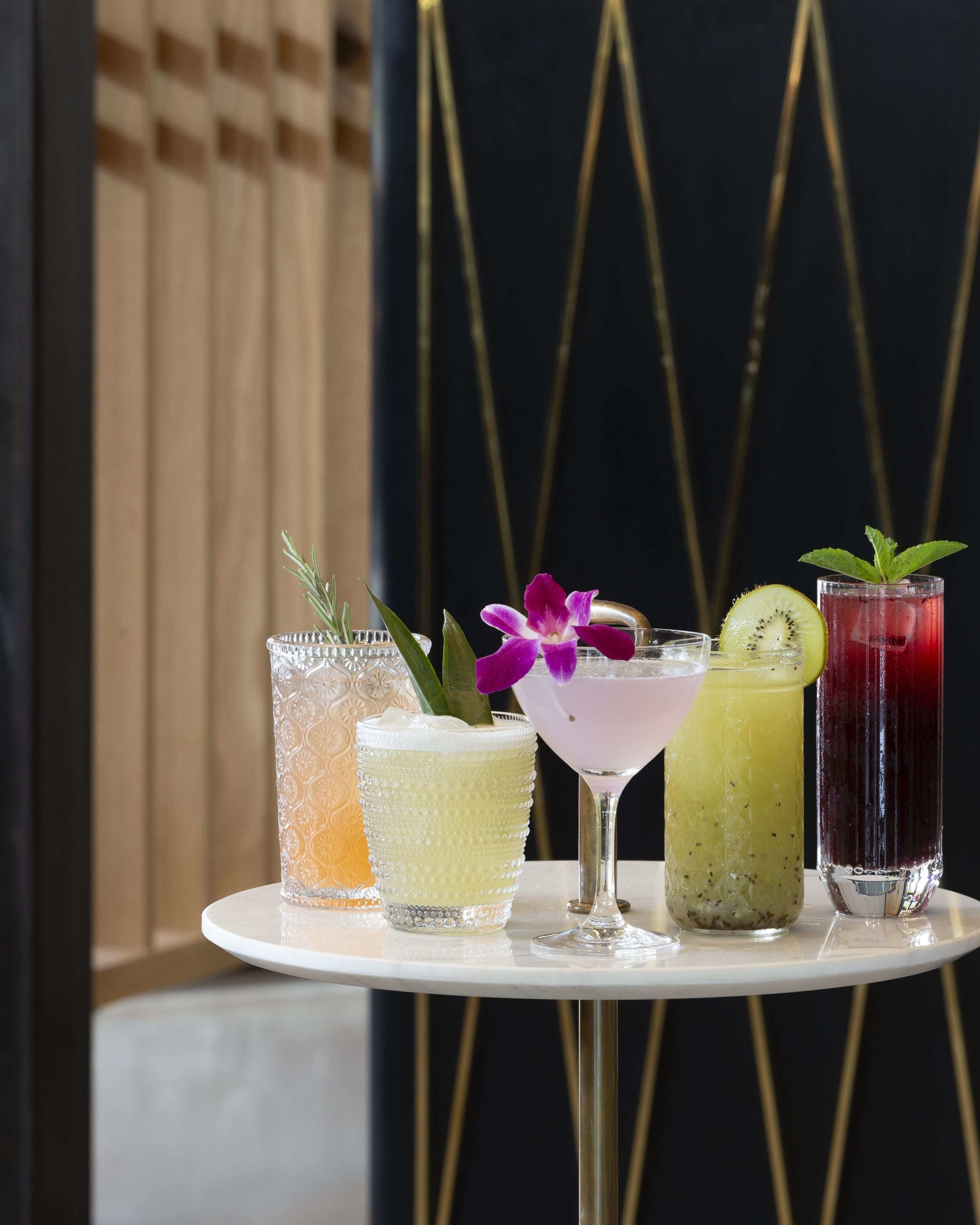 Une table avec quatre boissons différentes, chacune agrémentée d’une garniture originale.