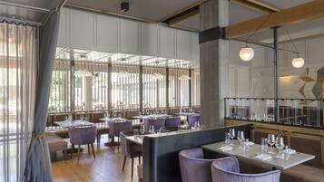 Un restaurante con techos altos, ventanas amplias y mobiliario moderno.