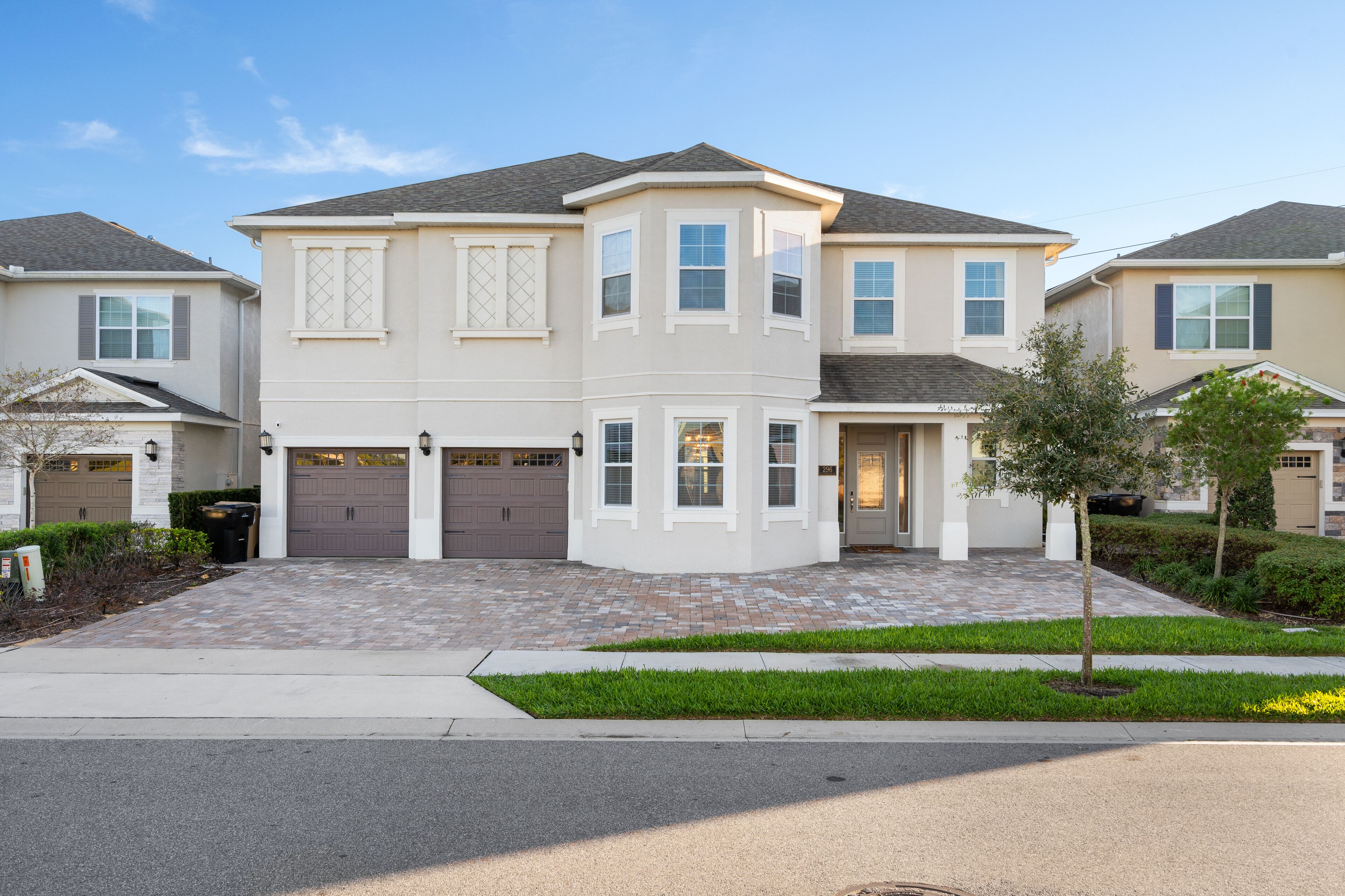 A two-story residential building with a garage, a driveway, and a well-maintained lawn.