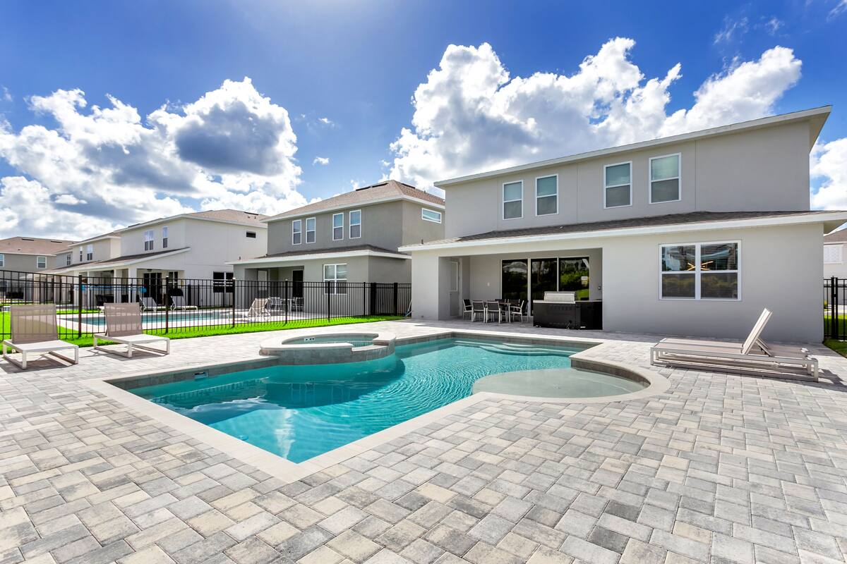 Un edificio residencial con piscina, mobiliario exterior y patio amurallado.