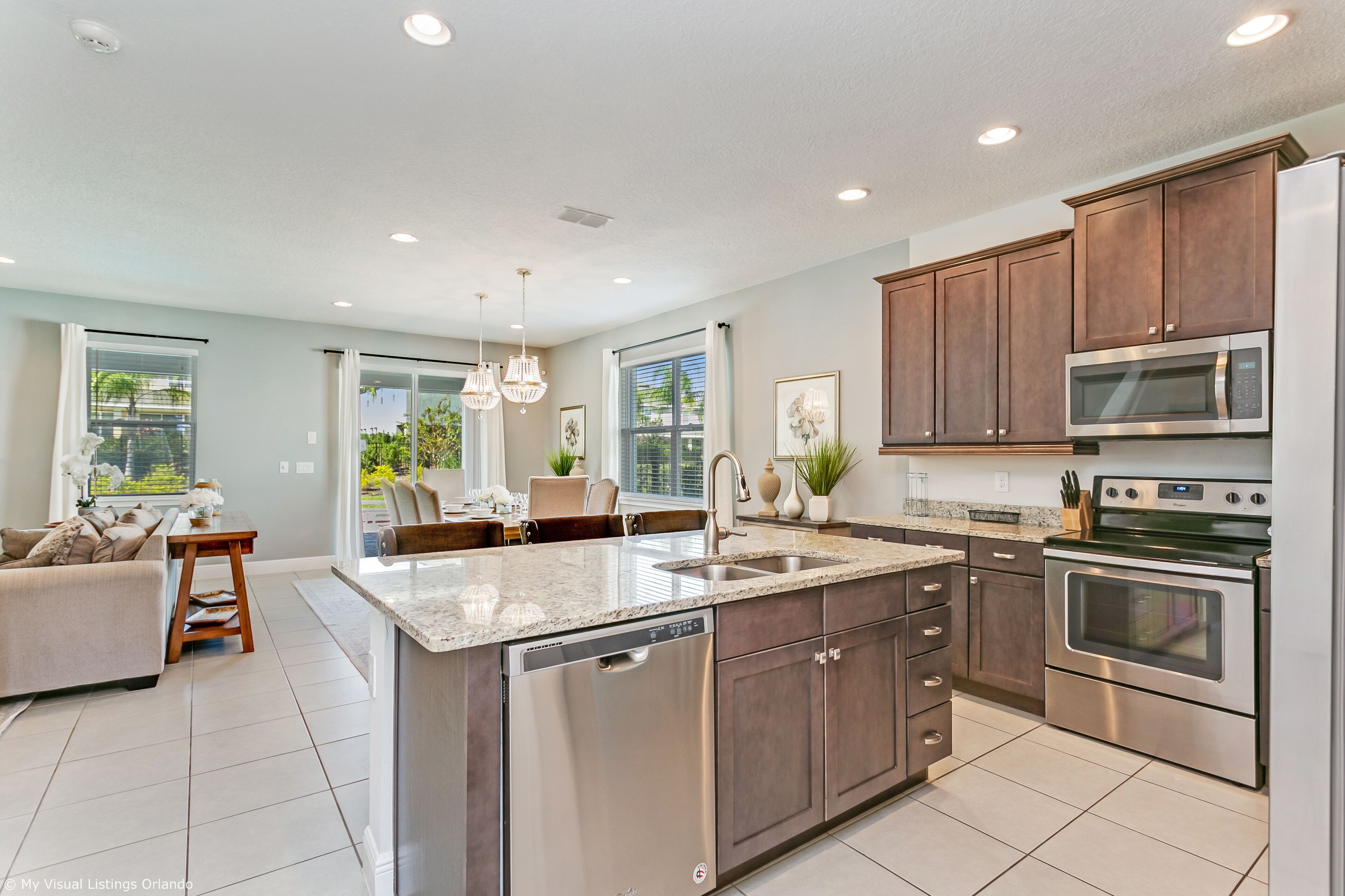A modern kitchen with a central island, stainless steel appliances, and a dining area with a sofa and table.