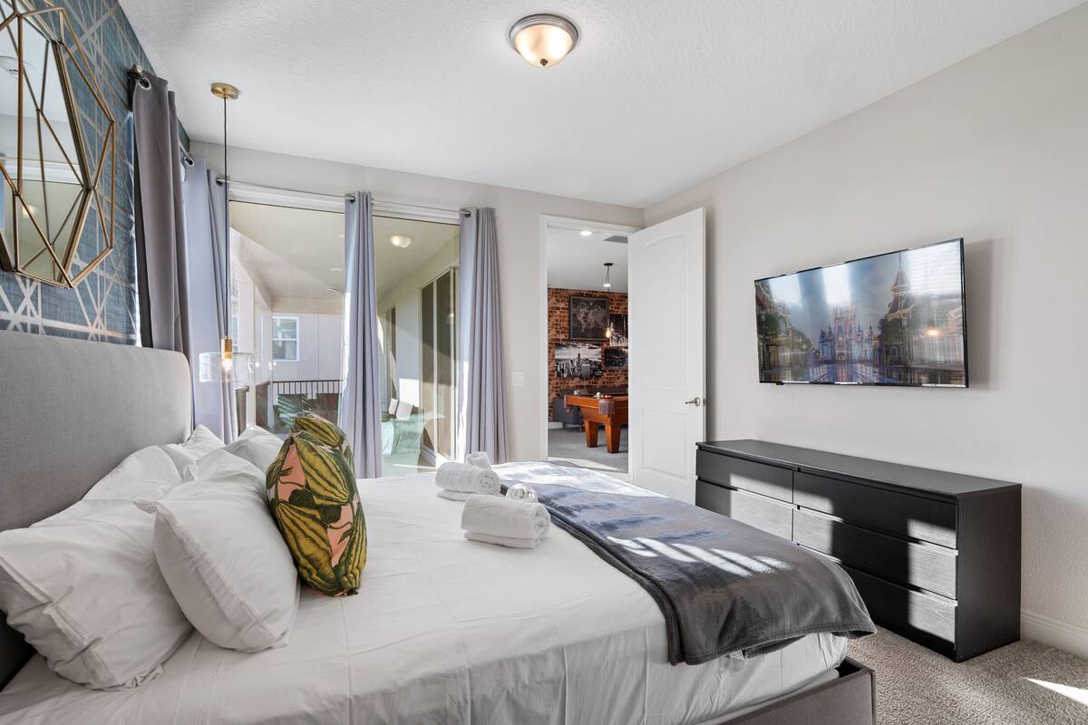 Una habitación de hotel moderna con una cama grande, un televisor de pantalla plana, un aparador y vistas a un paisaje urbano.