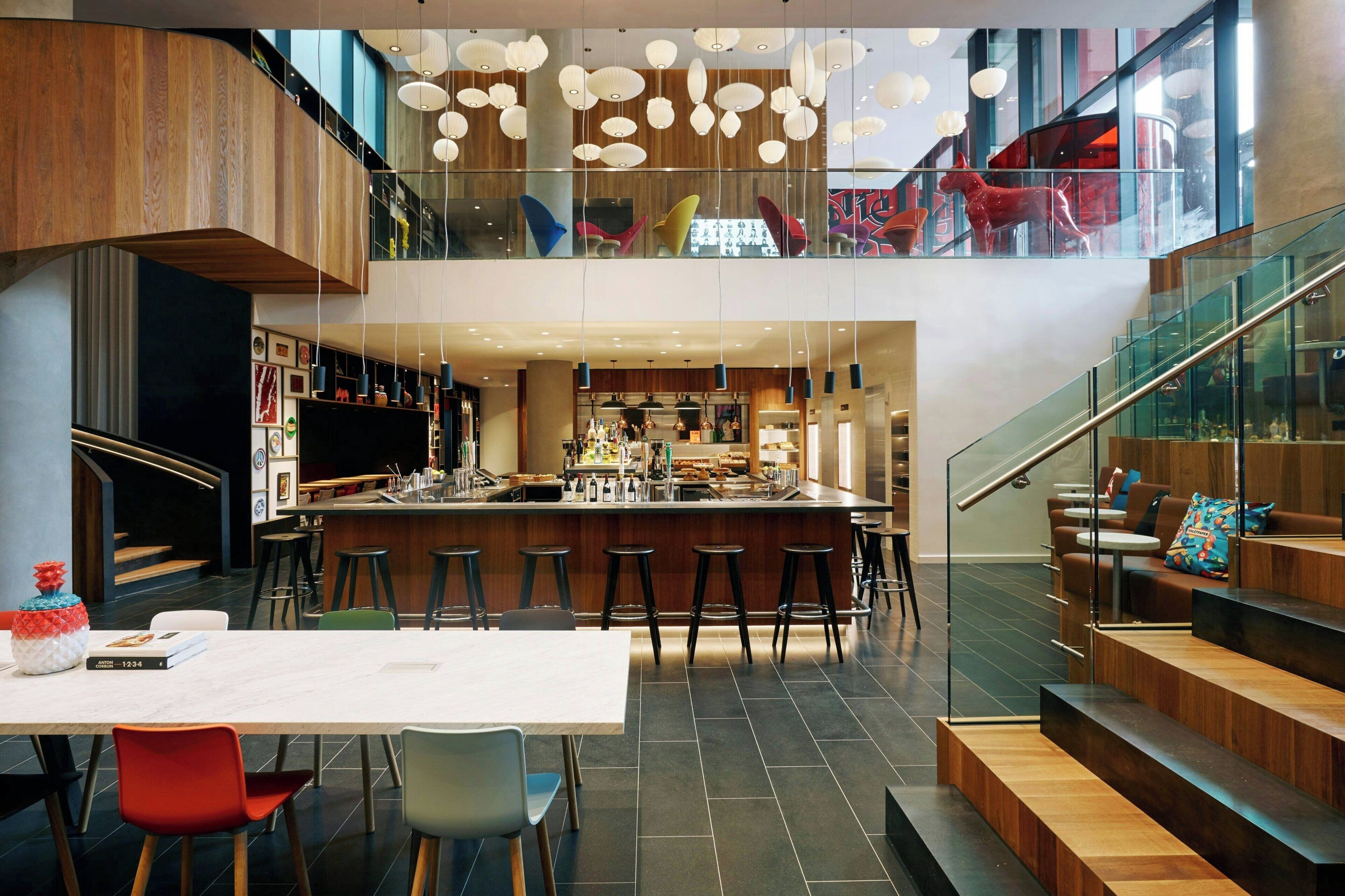 Un intérieur moderne avec un bar central, un espace salon et un escalier menant à un niveau supérieur.
