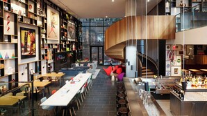 Un interior moderno con una larga mesa de comedor, diversas opciones de asiento, una zona de bar y una escalera que lleva a un nivel superior.