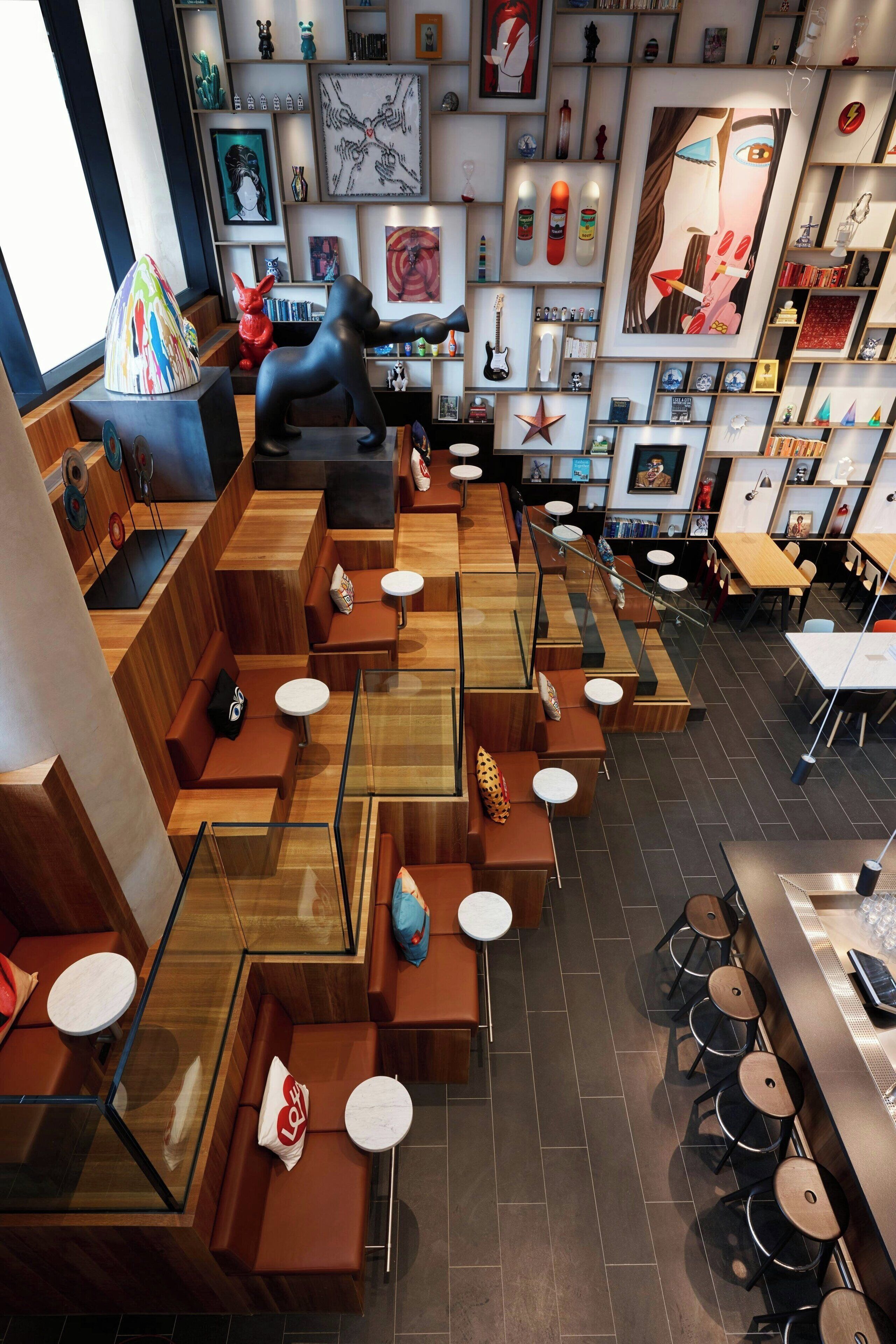 A modern restaurant with wooden seating, a bar area, and various artworks on the walls.