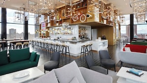 A modern bar area with a central island, seating arrangements, and a city view. - citizenM New York Bowery (New York)
