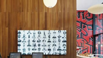 Una recepción con un gran collage de fotos en la pared, paneles de madera y lámparas colgantes.