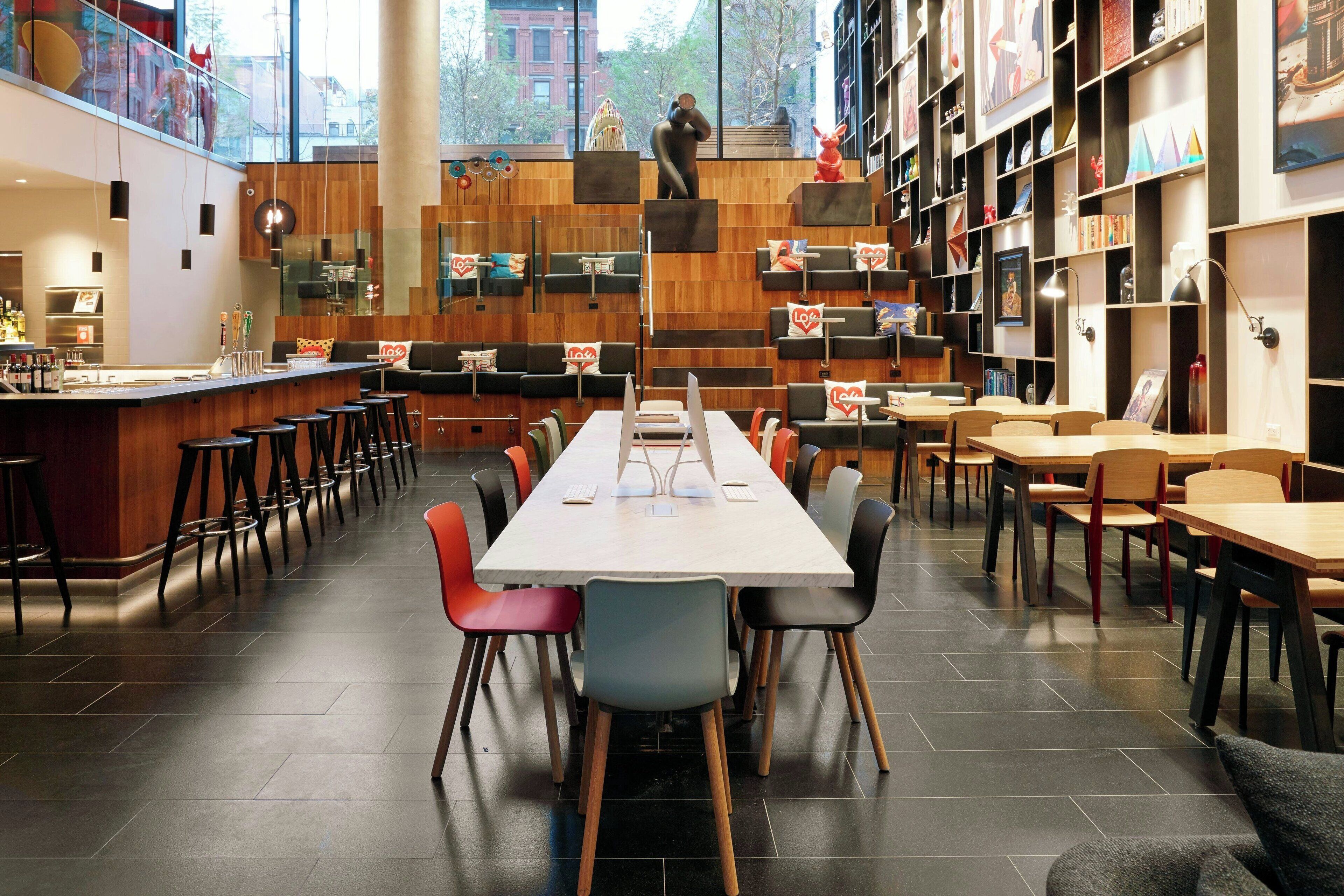 Une bibliothèque moderne dotée d’une longue table et de chaises, d’étagères et d’un coin bar.