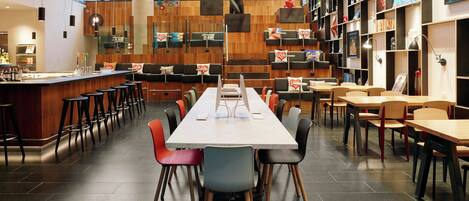 Une bibliothèque moderne dotée d’une longue table et de chaises, d’étagères et d’un coin bar.