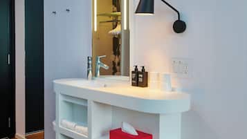 A modern bathroom with a white vanity, a mirror, and a red stool.