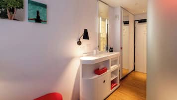 Uma casa de banho moderna com um lavatório branco, um espelho e uma cadeira vermelha.