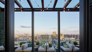 A rooftop terrace with a city view, furnished with sofas and small tables, under a pergola with string lights. - citizenM New York Bowery (New York)