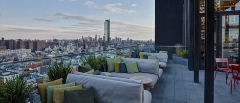 An outdoor seating area with a city view, modern furniture, and a glass railing.