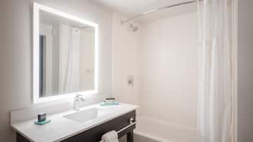 A modern bathroom with a large mirror, a sink, a shower, and a bathtub.