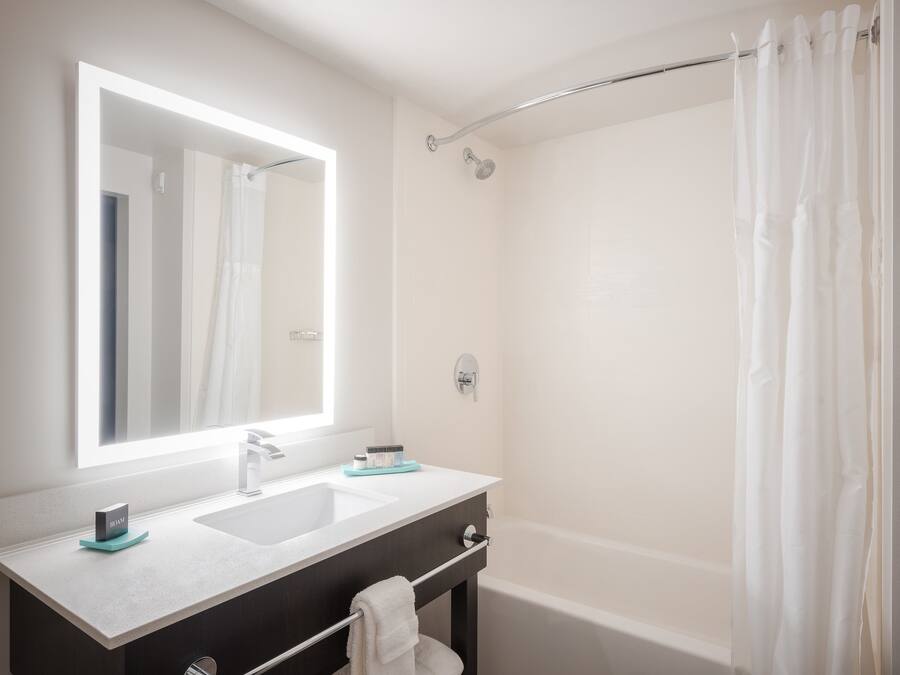 A modern bathroom with a large mirror, a sink, a shower, and a bathtub.