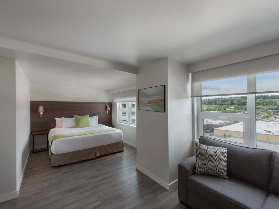Une chambre d’hôtel moderne avec un grand lit, un canapé et une vue sur la ville.