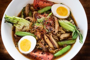 A bowl of ramen with noodles, vegetables, and a boiled egg.