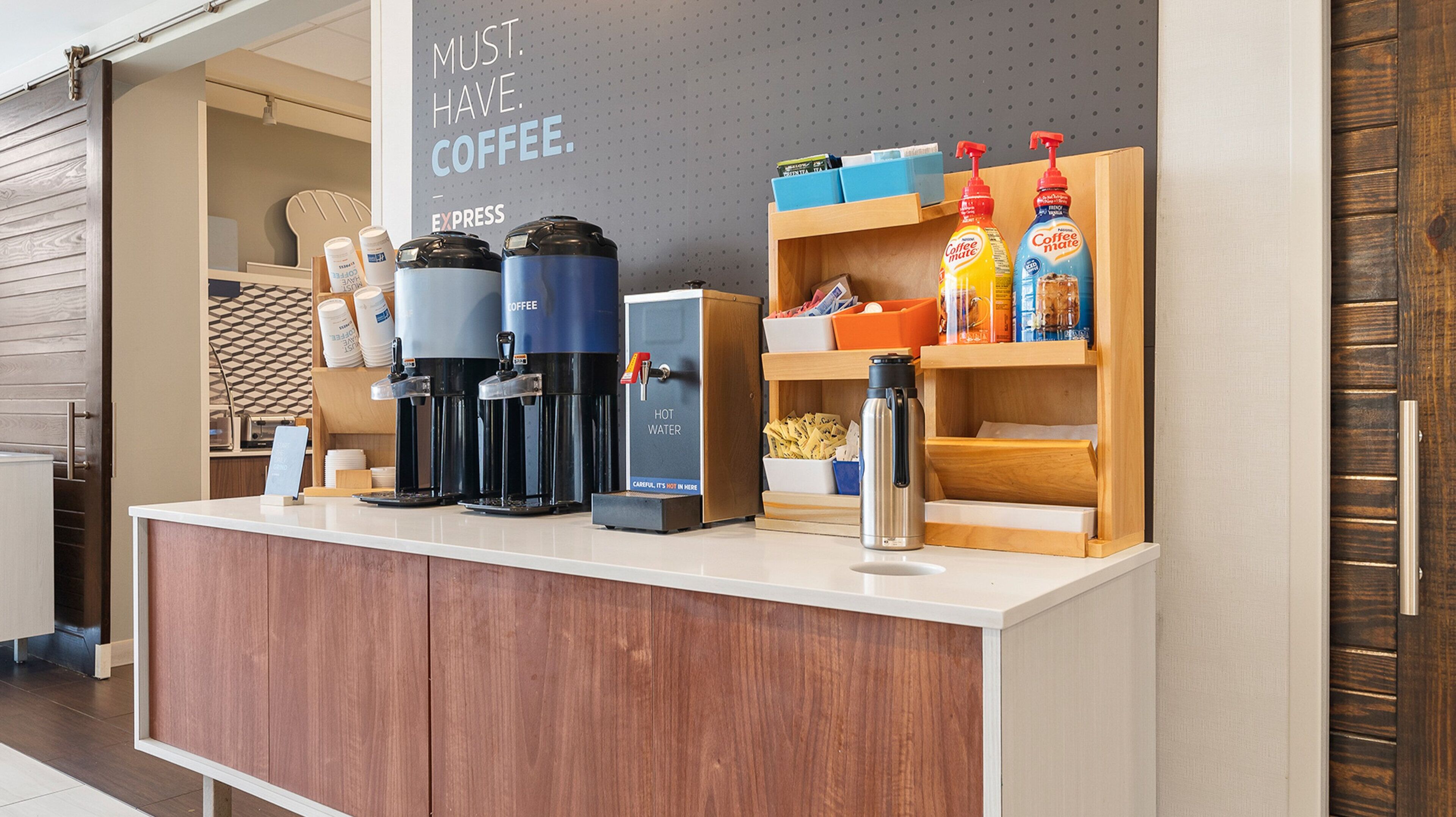 A coffee station with multiple coffee machines, a hot water dispenser, and coffee-related products.