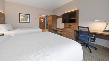 Een hotelkamer met een groot bed, een bureau met een computer, een televisie en een klein zitje.