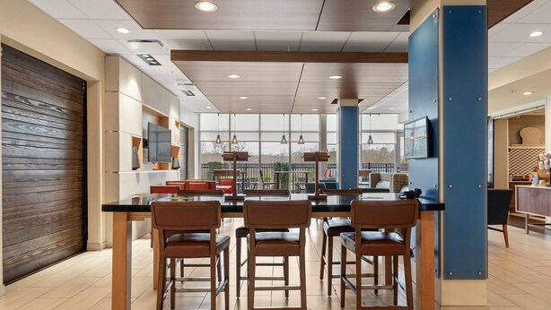 A modern kitchen with a central island, bar stools, and a large window offering a view of the outdoors. - Holiday Inn Express & Suites Macon North by IHG (Macon)