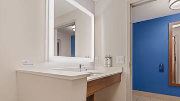 Une salle de bain moderne avec un lavabo blanc, un grand miroir et un mur d’accent bleu.