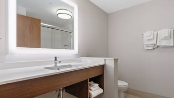 Een moderne badkamer met een witte wastafel, een spiegel, een wastafel en een toilet.
