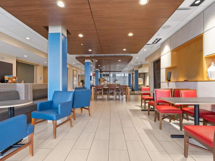 A modern cafe with blue and red seating, wooden accents, and a coffee station.