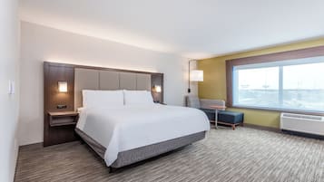Habitación de hotel con una cama grande, una mesita de noche, un escritorio con silla, una ventana con vistas y un calentador en la pared.