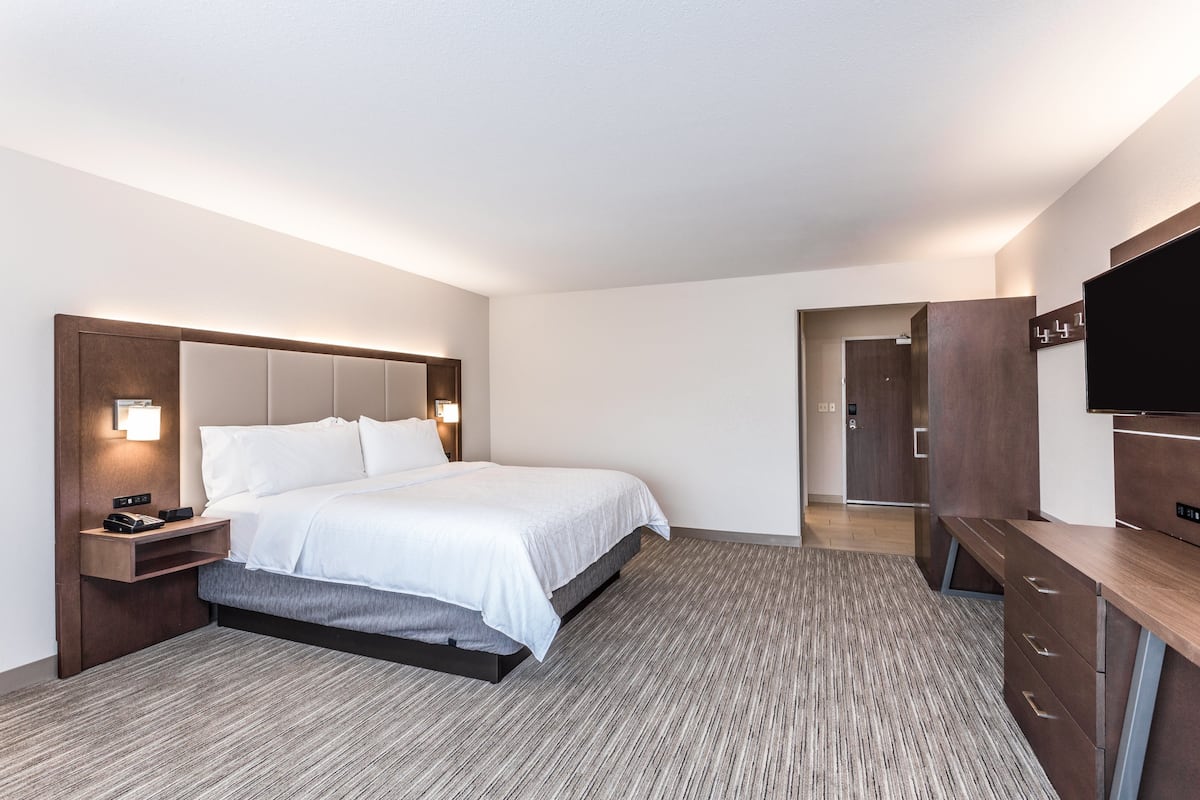 Une chambre d’hôtel moderne dotée d’un grand lit, de tables de chevet, d’un téléviseur à écran plat et d’une armoire.